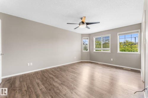 Wood-finish flooring throughout, modern ceiling fan with integrated lighting, multiple windows providing natural illumination, light neutral wall paint, and white trim accents - 2060 Brennan Crescent Nw, Edmonton, AB 