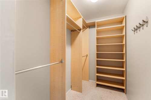 Custom closet system featuring light wood-finish shelving, multiple hanging rods, and an integrated shoe rack - 2060 Brennan Crescent Nw, Edmonton, AB 