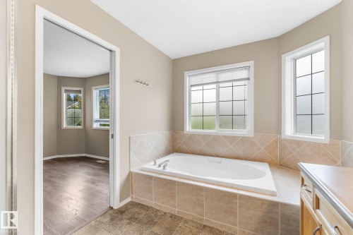 Built-in soaking tub with tiled surround, multiple windows, and wood-finish flooring - 2060 Brennan Crescent Nw, Edmonton, AB 