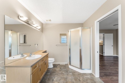 Double vanity with dual sinks, wood-finish cabinetry, and a large wall-mounted mirror - 2060 Brennan Crescent Nw, Edmonton, AB 