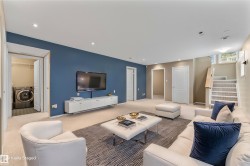 Recessed lighting, wall-mounted television, built-in entertainment console, carpeted flooring, and a laundry area with appliances - 