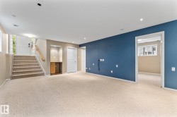 Carpeted flooring throughout, recessed lighting, built-in wooden cabinet with shelving, and staircase with wooden handrail - 