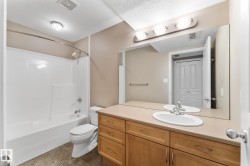 Bathroom featuring a built-in wood-finish vanity with an integrated sink, a large wall-mounted mirror, a tub/shower combination, and tiled flooring - 