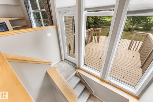 Expansive deck with wood railing, large windows with blinds, wood-finish flooring, and carpeted stairs with wood handrails - 2060 Brennan Crescent Nw, Edmonton, AB 