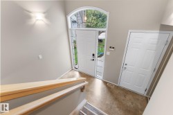 Foyer featuring an arched transom window, a paneled entry door with sidelights, a second paneled door, and wood-finish flooring - 