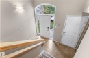 Foyer featuring an arched transom window, a paneled entry door with sidelights, a second paneled door, and wood-finish flooring - 2060 Brennan Crescent Nw, Edmonton, AB 