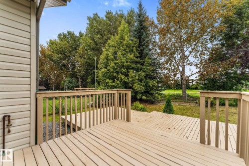 Multi-level wood deck with wood railings, leading to a landscaped yard with mature trees - 2060 Brennan Crescent Nw, Edmonton, AB 