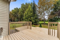 Multi-level wood deck with wood railings, leading to a landscaped yard with mature trees - 