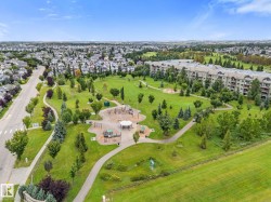 Expansive green space featuring a playground, walking paths, and mature trees - 