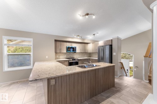 Kitchen featuring wood-finish cabinetry, light-toned countertops, and a dual basin sink - 2060 Brennan Crescent Nw, Edmonton, AB 