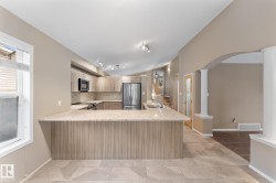 Kitchen featuring light wood-finish cabinetry, stainless steel appliances, a breakfast bar, and track lighting - 