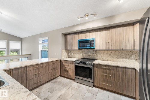 Kitchen featuring light wood-finish cabinetry, light-toned countertops, stainless steel appliances, and tile flooring - 2060 Brennan Crescent Nw, Edmonton, AB 