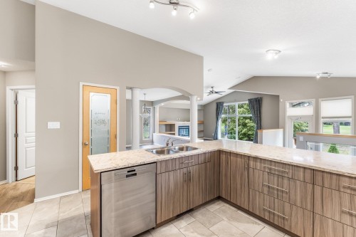 Kitchen featuring light-toned cabinetry, granite-style countertops, stainless steel sink, and stainless steel dishwasher - 2060 Brennan Crescent Nw, Edmonton, AB 