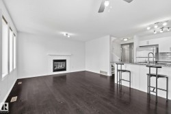Wood-finish flooring throughout, with a tiled fireplace and white mantel - 