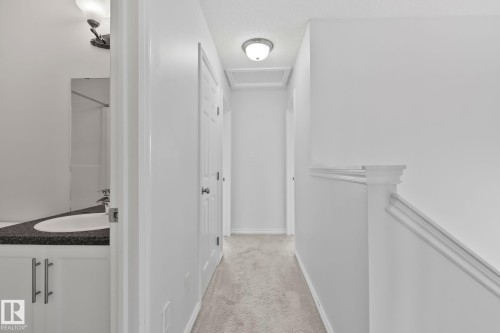 Hallway with neutral carpet, white walls, and flush mount lighting - 9523 Simpson Crest Nw, Edmonton, AB 