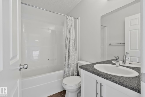 White vanity with brushed nickel hardware, integrated sink, and dark speckled countertop - 9523 Simpson Crest Nw, Edmonton, AB 