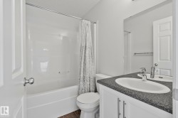 White vanity with brushed nickel hardware, integrated sink, and dark speckled countertop - 