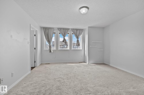 Light-colored carpeting, multiple windows providing natural illumination, and a ceiling-mounted light fixture - 9523 Simpson Crest Nw, Edmonton, AB 