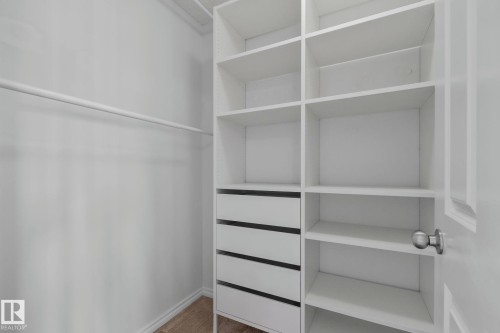 Custom closet system featuring multiple open shelves, four integrated drawers, and a hanging rod - 9523 Simpson Crest Nw, Edmonton, AB 