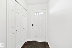 Entryway with wood-finish flooring, white paneled door with transom window, and built-in bi-fold closet - 