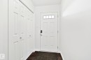 Entryway with wood-finish flooring, white paneled door with transom window, and built-in bi-fold closet - 9523 Simpson Court Nw, Edmonton, AB 