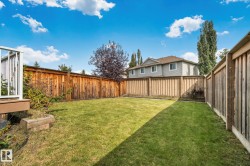 Expansive backyard featuring a manicured lawn, wood fencing, and a raised wood deck with white railings - 