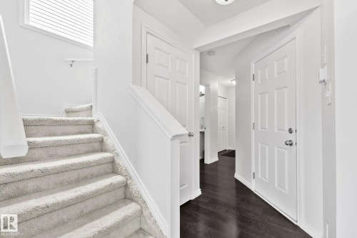 Staircase with light-toned carpeting and white railing - 9523 Simpson Crest Nw, Edmonton, AB 