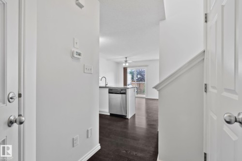 Open-concept layout with wood-finish flooring, a kitchen island, and stainless steel appliances - 9523 Simpson Crest Nw, Edmonton, AB 