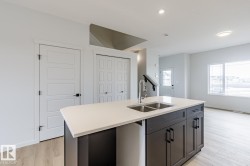 Kitchen island featuring a dual-basin stainless steel sink with a high-arc faucet, light-toned countertop, and dark cabinetry - 