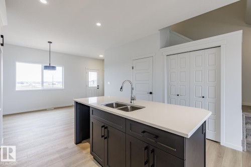 Kitchen island featuring a double-basin stainless steel sink with a gooseneck faucet - 3603 40 Avenue, Beaumont, AB - Indoor Photo Showing Kitchen With Double Sink