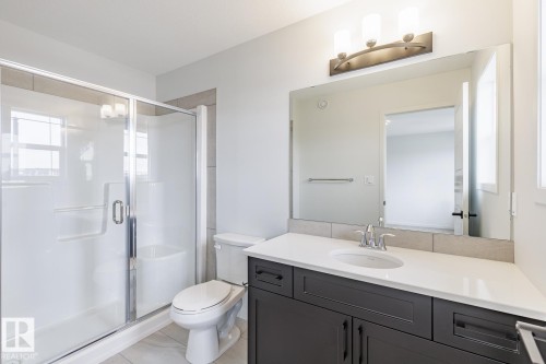 Bathroom featuring a dark wood-finish vanity with a white countertop, an undermount sink, and a chrome faucet - 3603 40 Avenue, Beaumont, AB - Indoor Photo Showing Bathroom