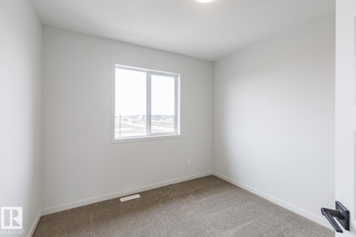 Neutral-toned carpet flooring and white baseboards - 3603 40 Avenue, Beaumont, AB - Indoor Photo Showing Other Room