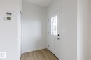Entryway featuring a white door with decorative glass inserts, wood-finish flooring, and light gray wall paint - 3603 40 Avenue, Beaumont, AB  - Indoor Photo Showing Other Room 