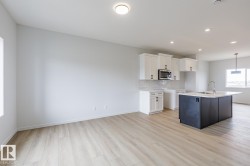 Open-concept living space featuring wood-finish flooring, recessed lighting, and a kitchen island with seating - 