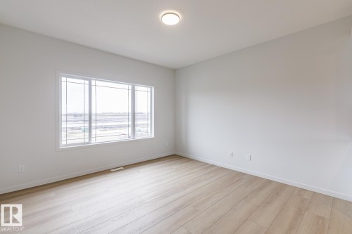 Spacious room featuring a large window with white framing, light wood-finish flooring, recessed ceiling lighting, and neutral wall tones - 3603 40 Avenue, Beaumont, AB - Indoor Photo Showing Other Room