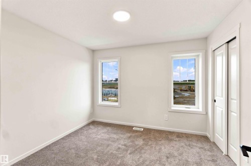 White walls, two windows with white trim, gray carpeting, and a white bi-fold closet door - 7097 Rosenthal Drive Nw, Edmonton, AB 