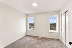 White walls, two windows with white trim, gray carpeting, and a white bi-fold closet door - 