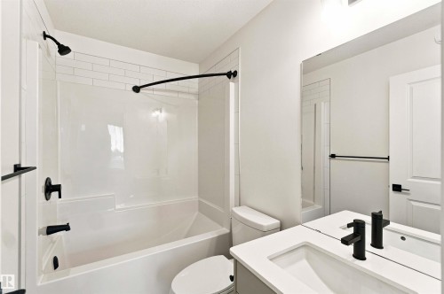 White subway tile tub surround, matte black shower fixtures, vanity with integrated sink, matte black vanity faucet, and a large wall-mounted mirror - 7097 Rosenthal Drive Nw, Edmonton, AB 