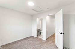 Carpeted interior space with white walls, a flush-mounted ceiling light, and white panel doors with black hardware - 