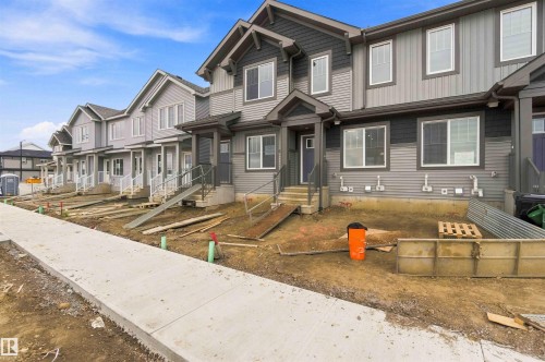 Modern townhouse exteriors featuring multi-toned siding, white-trimmed windows, covered entryways, and gabled rooflines - 7097 Rosenthal Drive Nw, Edmonton, AB 