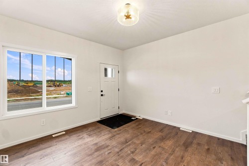 Wood-finish flooring, white trim, recessed panel door with clear glass inserts, and a contemporary flush mount light fixture - 7097 Rosenthal Drive Nw, Edmonton, AB 
