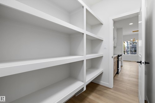 Built-in shelving for organized storage, light wood-finish flooring, and a white interior door with matte black hardware - 1780 Crossbill Loop Nw, Edmonton, AB 