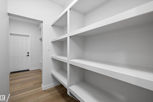 Built-in shelving with multiple storage levels, light wood-finish flooring, and a paneled entry door - 1780 Crossbill Loop Nw, Edmonton, AB 