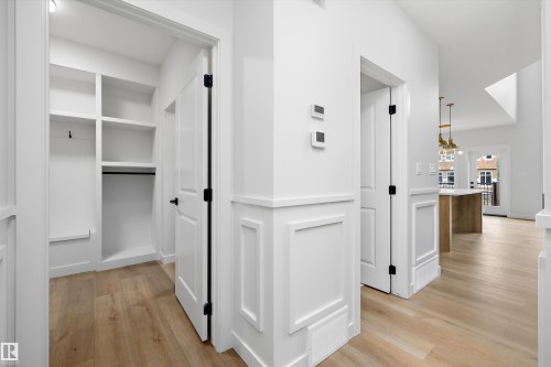 Wood-finish flooring, white paneled wall detailing, built-in closet shelving, and a built-in closet rod - 1780 Crossbill Loop Nw, Edmonton, AB 