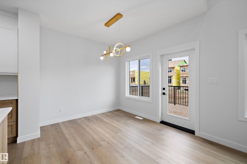 Wood-finish flooring, white walls, contemporary lighting fixture, glass-panel door, and a built-in railing - 1780 Crossbill Loop Nw, Edmonton, AB 