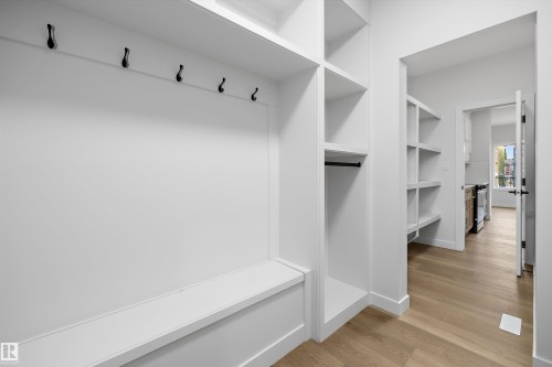 Built-in hall tree with bench and coat hooks, open shelving, and light wood-finish flooring - 1780 Crossbill Loop Nw, Edmonton, AB 