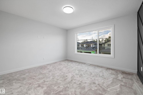 Neutral-toned carpeting, white walls, and a large window with white trim - 1780 Crossbill Loop Nw, Edmonton, AB 