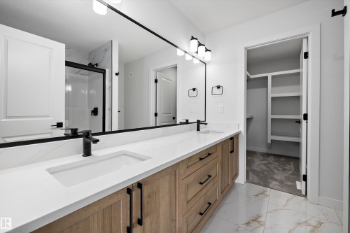 Dual vanity with white undermount sinks, wood-finish cabinetry, and matte black hardware - 1780 Crossbill Loop Nw, Edmonton, AB 