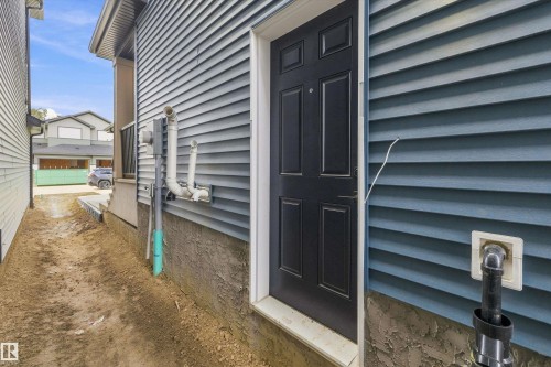 Blue horizontal siding with a dark entry door and exposed foundation - 1780 Crossbill Loop Nw, Edmonton, AB 