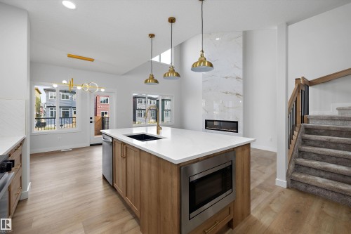 Kitchen island with integrated microwave, stainless steel appliances, and wood-finish flooring - 1780 Crossbill Loop Nw, Edmonton, AB 